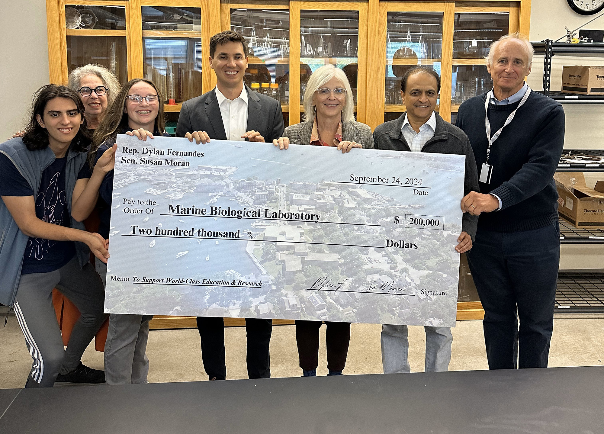 People holding a big check made out to MBL for 200,000 dollars.