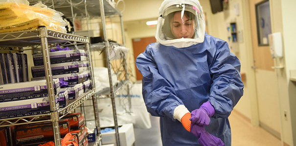 A medical worker dons personal protective equipment. 