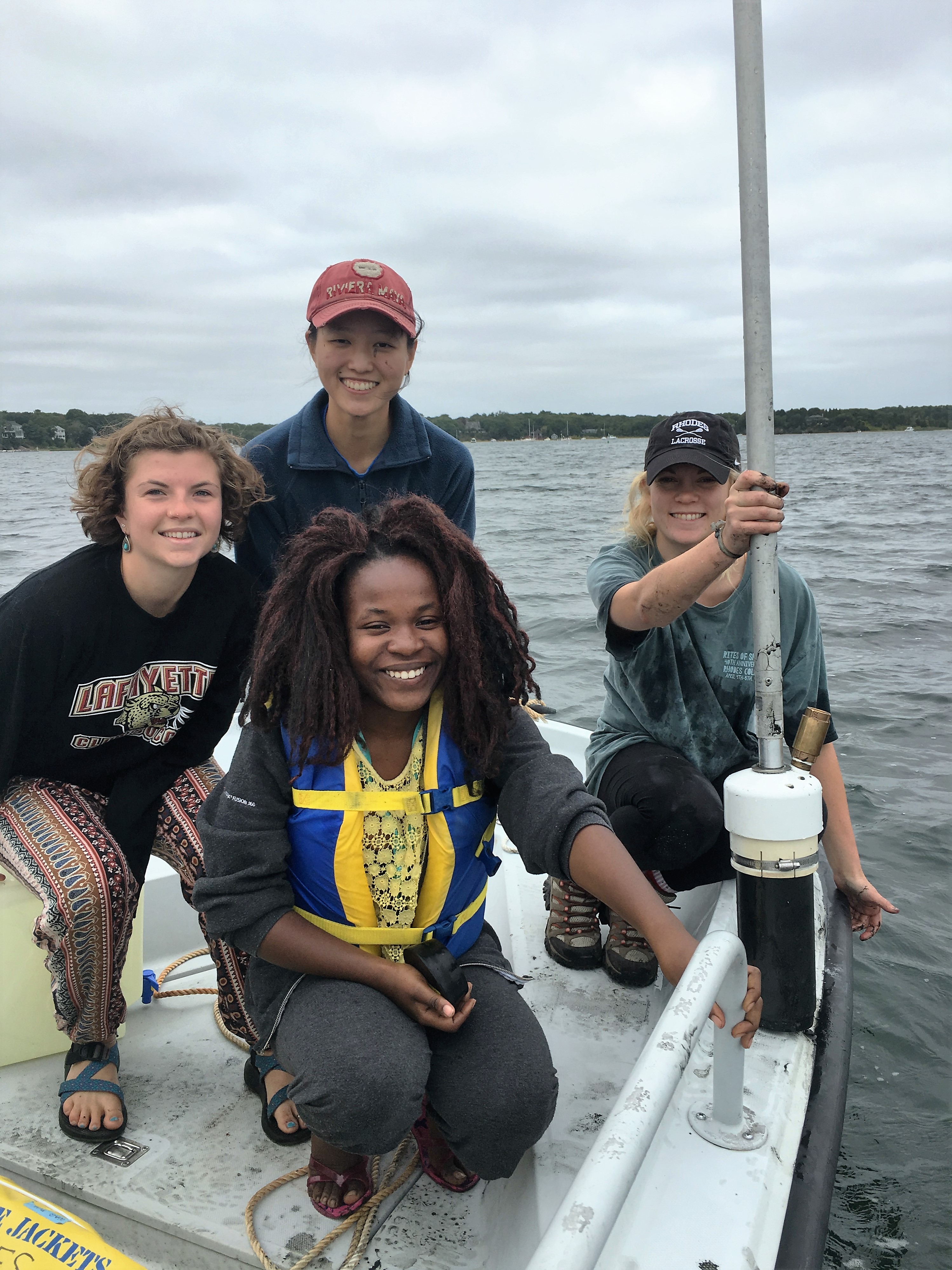 Semester in Environmental Science (SES) students taking core samples in Waquoit Bay, Falmouth, in 2016. From left: Misty Earisman (Lafayette College), Hannah Gershone (Mount Holyoke College, standing), Catherine Ballali (Earlham College, kneeling) and Erin Gleeson (Rhodes College). Credit: Alison Maksym