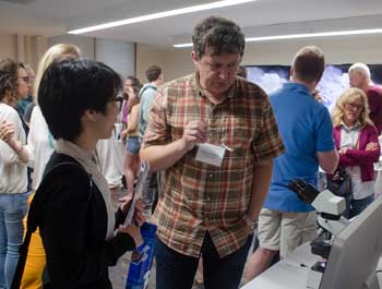 MBL scientist and microscope developer Michael Shribak explains his innovations to MBL summer science writer Jennifer Tsang  in the event's demo room. Credit: Emily Zollo