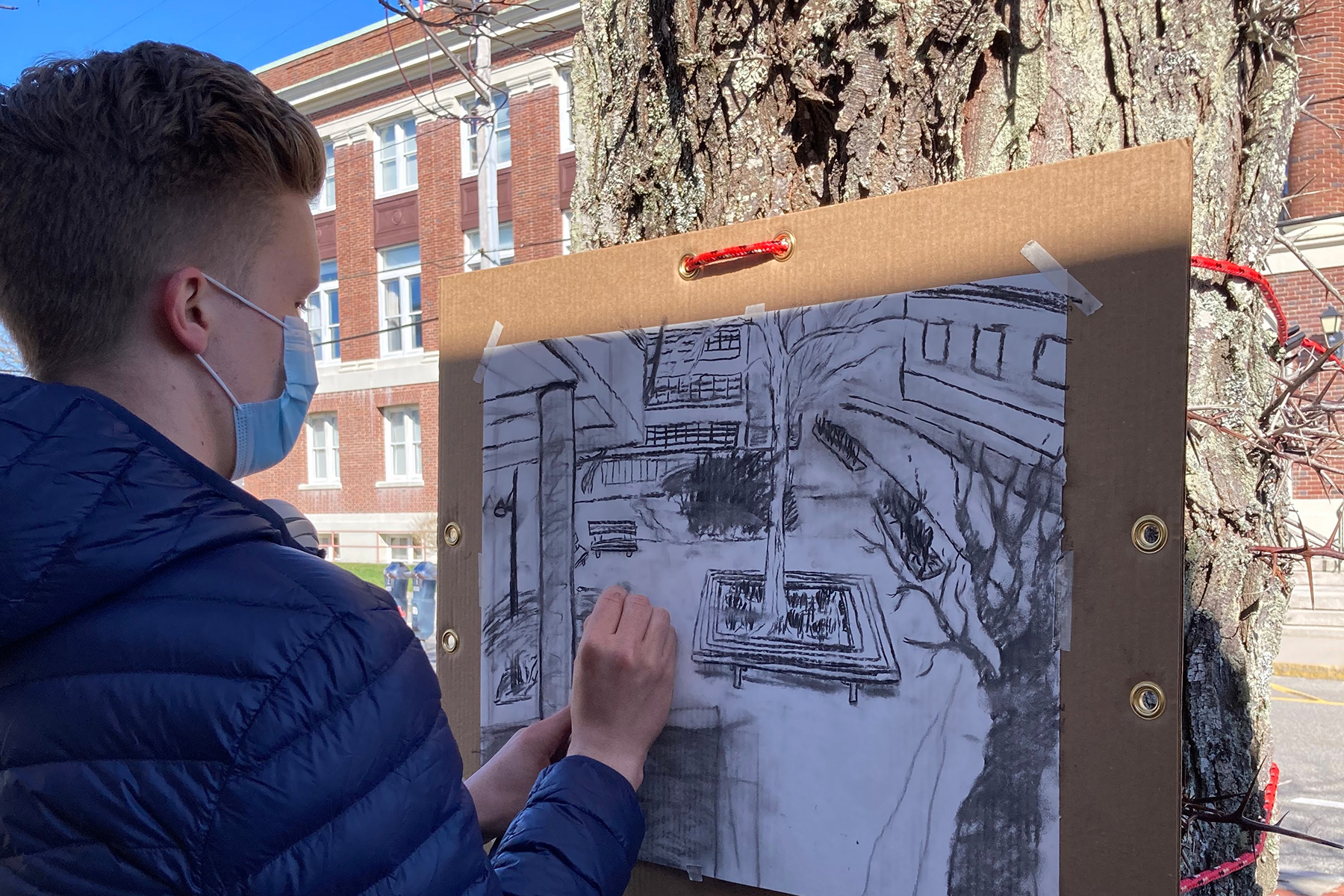 UChicago student Branson Scott-Starr doing a charcoal drawing in the MBL Quad for the Visual Language: On Images course. Credit: Frances Lee. 