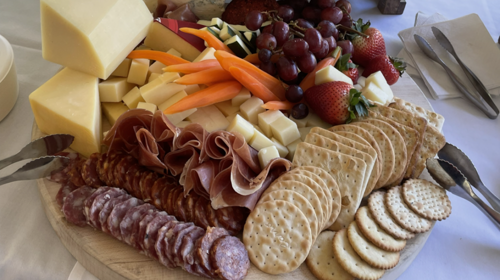 Charcuterie plate with meats, cheeses, veggies, fruits and crackers.