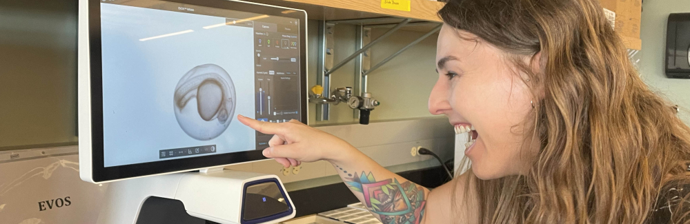 A scientist grins while examining an embryo.