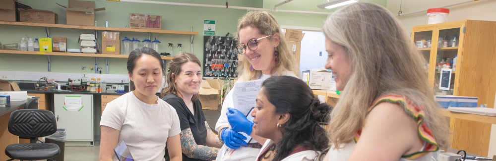 Scientists gather around a computer in the lab.