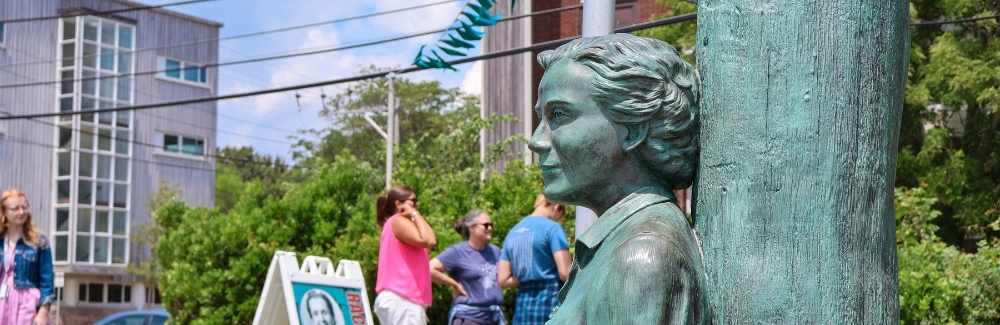 A statue of Rachel Carson with people in background