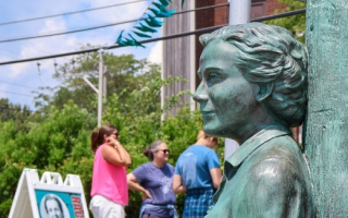 A statue of Rachel Carson with people in background