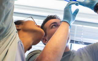 This photo shows two students holding up two containers filled with blue colored gels and looking up at them.