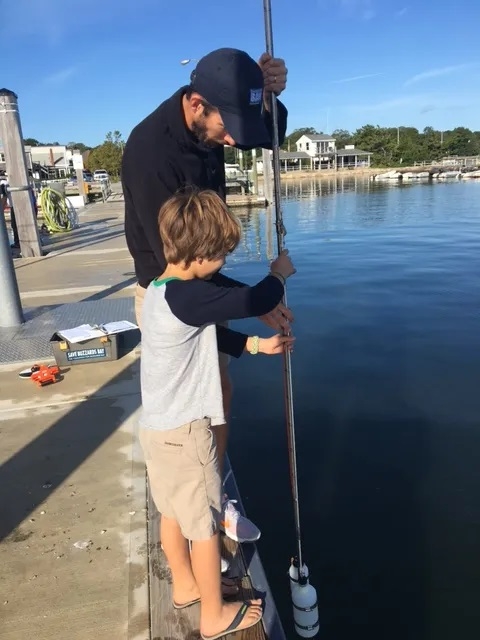 Baywatcher volunteer Marc Bellanger and son use a sampling pole to collect a water sample in Marion, Mass. Credit: Buzzards Bay Coalition