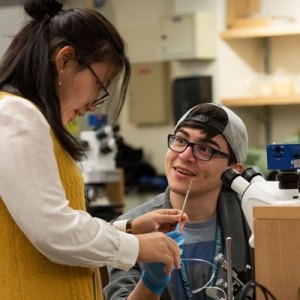 Eve Cai of St. Anne’s-Belfield School watches as MBL Research Assistant Anthony Rodríguez-Vargas shows her how to use a microinjection needle to conduct CRISPR Cas9 gene editing.