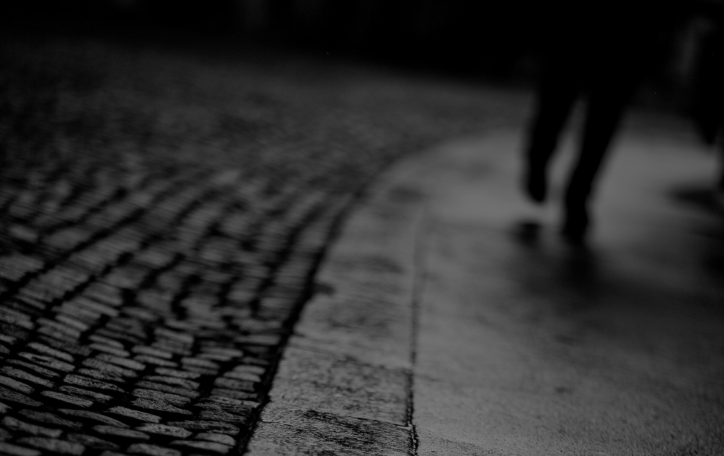 dark cobblestone street with person walking in background