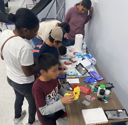 Volunteers help children prepare samples to view on their foldscopes