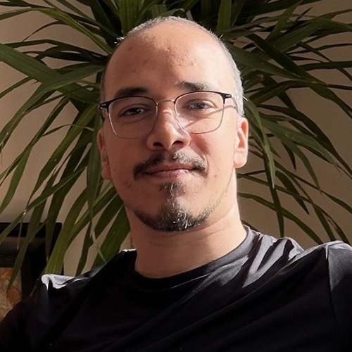 Main with short dark har, wearing glasses and a dark shirt.