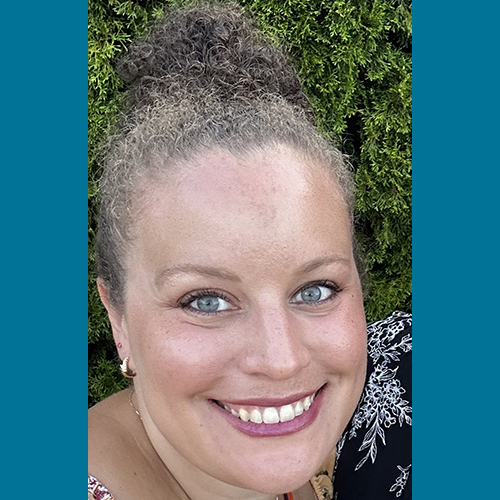 Smiling woman with curly brown hair in an updo.