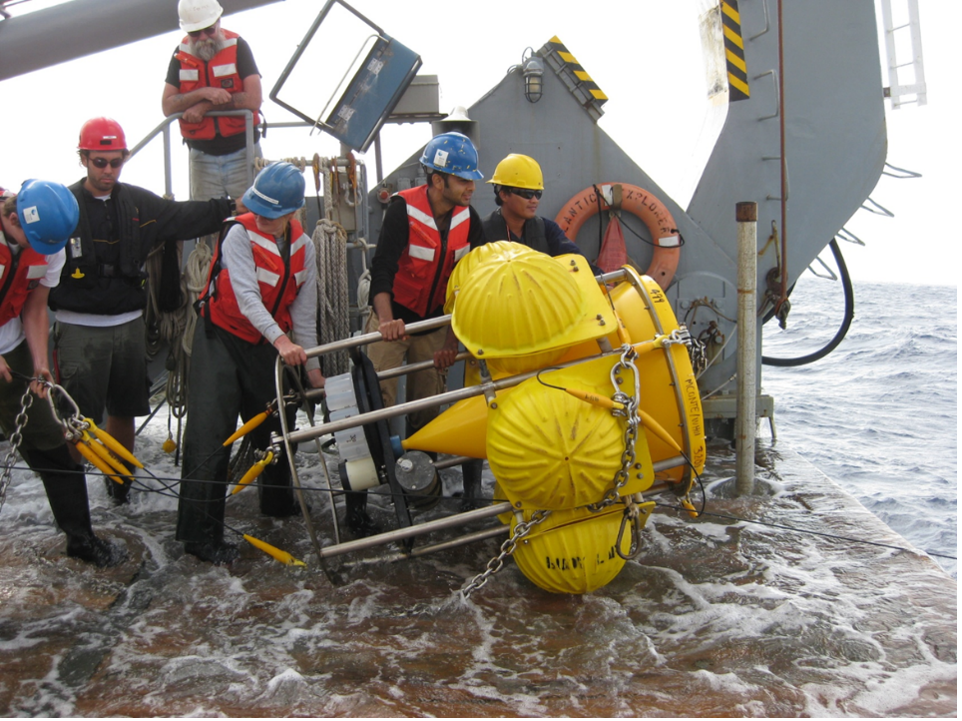 This photo shows MBL scientists on a ship holding a big contraption.