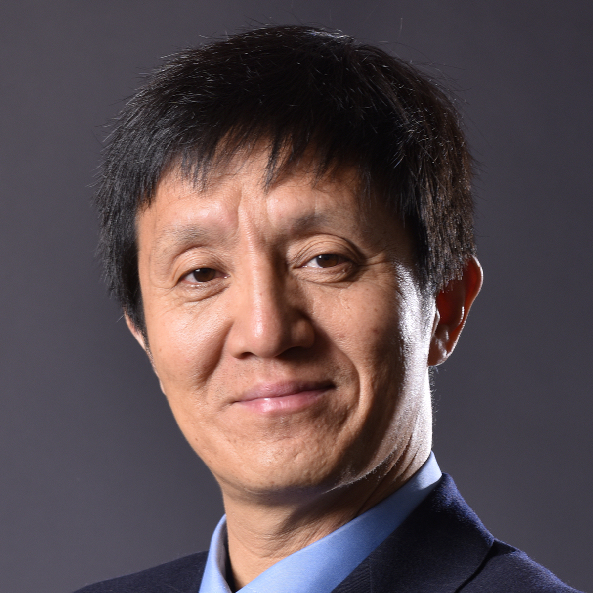 Smiling man with short dark hair wearing a blue suit.