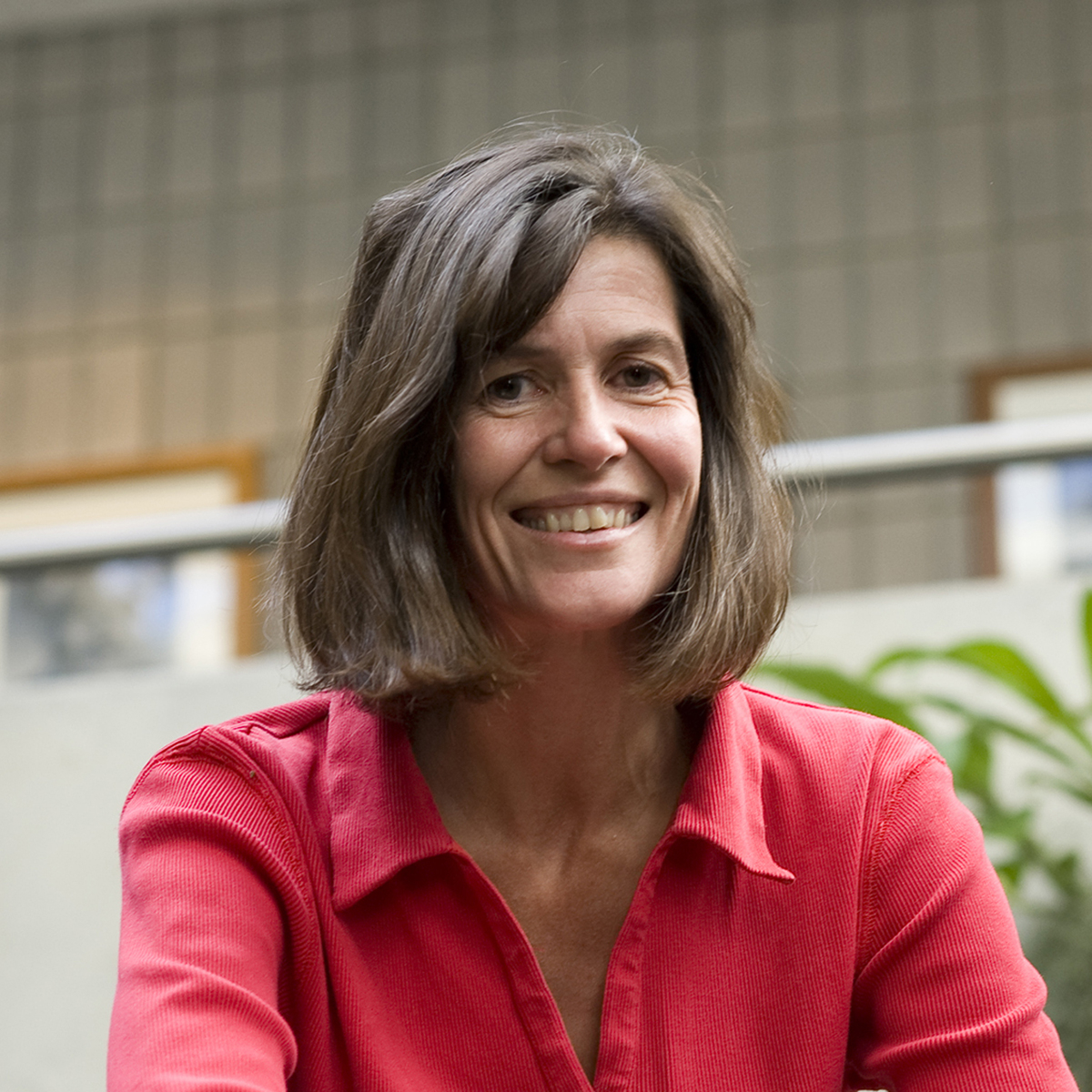 Smiling woman with long dark brown hair wearing a red shirt.