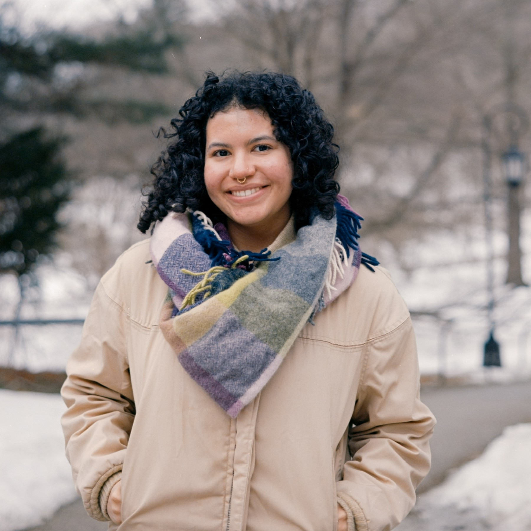 Female presenting person standing with snow in background.