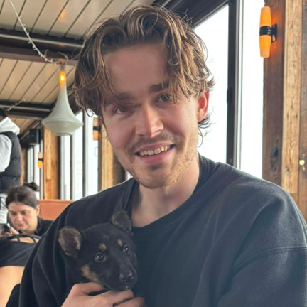 Male presenting person holding a puppy.