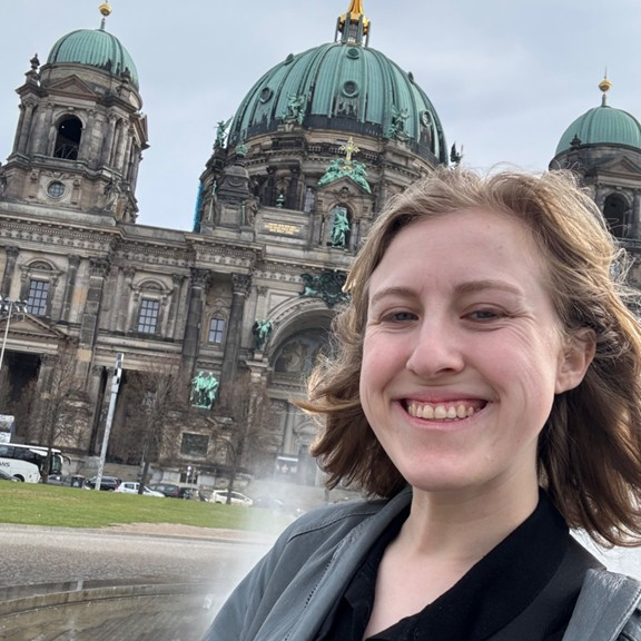 Female presenting person standing in front of the Berlin Cathedral.