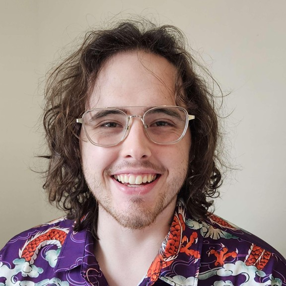 Male presenting person with dark hair and glasses.