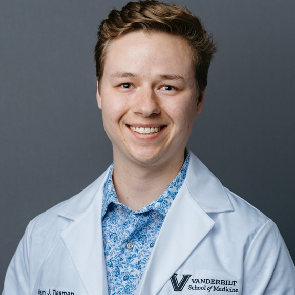 Male presenting person wearing a lab coat.