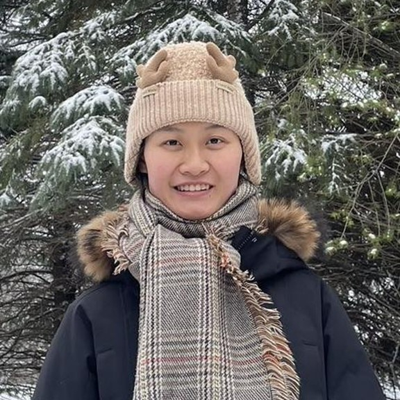 Female presenting person in coat and hat in winter.