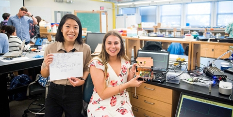 Christina Ford and Alyssa Condie display the plans for and the patch clamp amplifier that they built from scratch in the "Proteins in Action" course. 