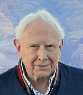 Older man with white hair wearing a blue jacket.