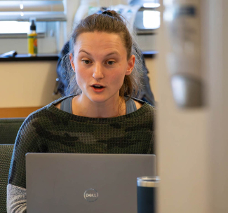 A scientist in the lab engages with a reporter on a zoom call.