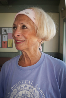 Female presenting person with short blond hair wearing an MBL shirt.